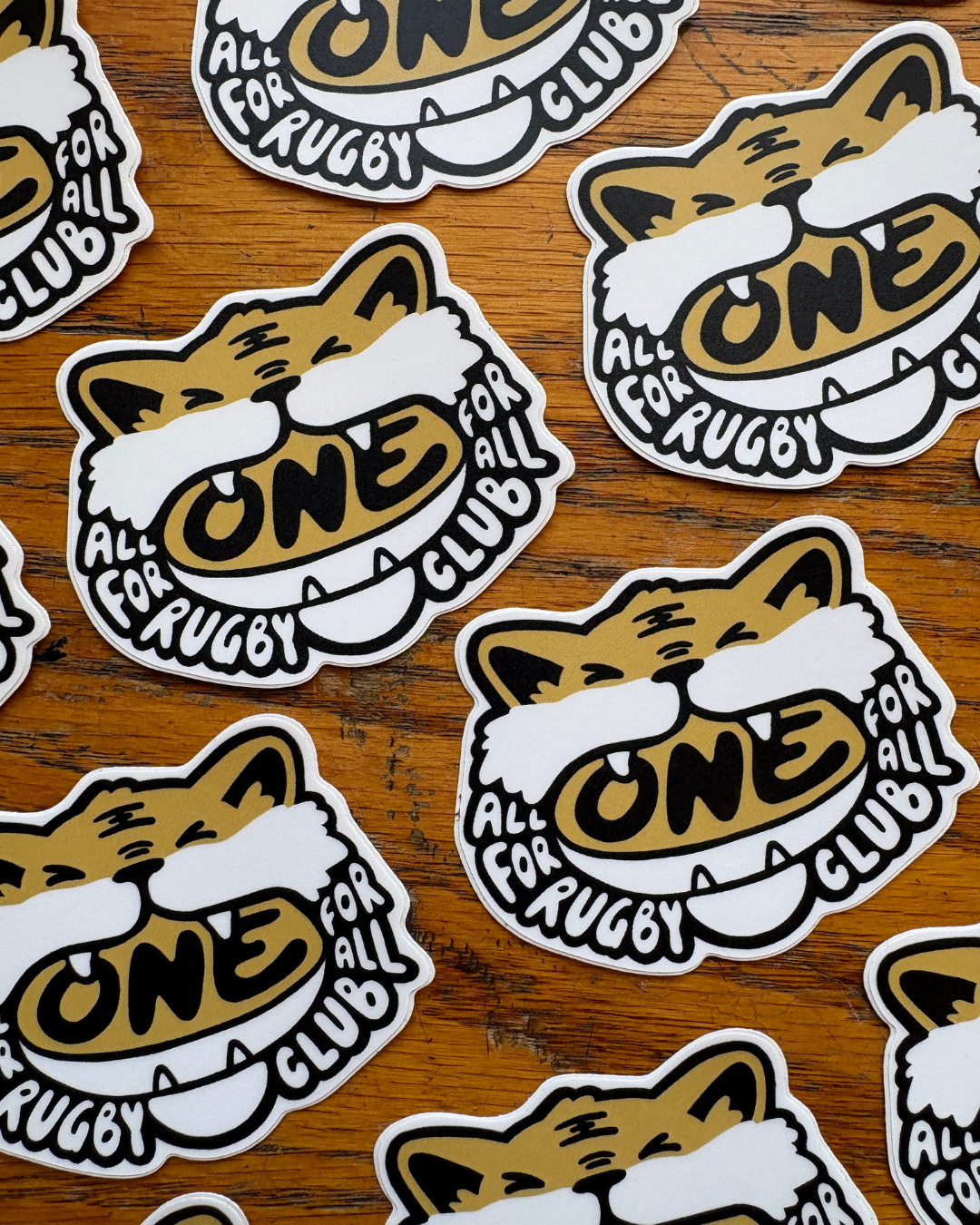 Repeating rows of stickers of cartoon tiger biting down on a rugby ball