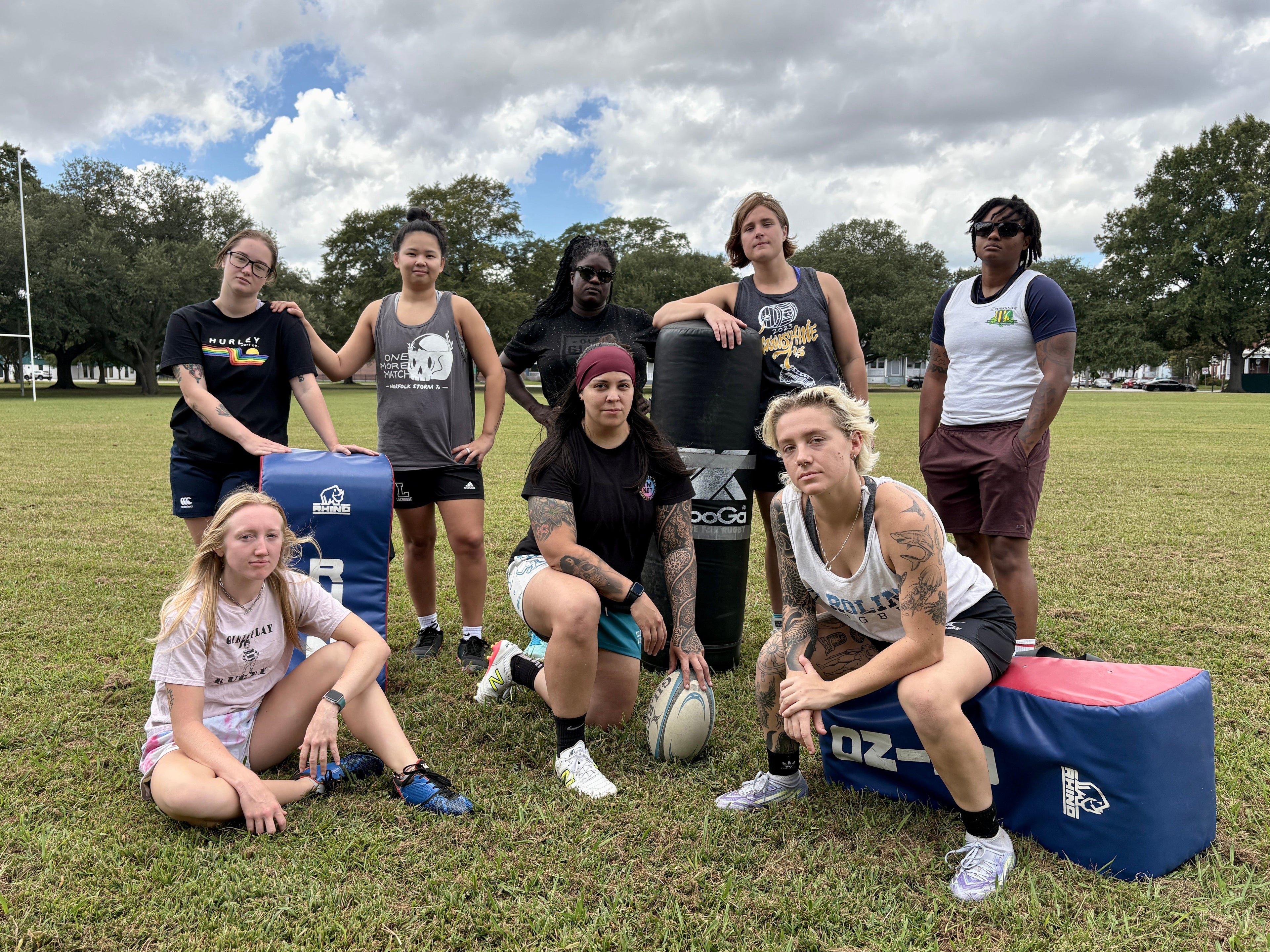 Group of rugby players in plain clothes posing on a field